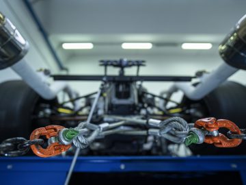 Achteraanzicht van een Lamborghini Formule 1-auto in een garage, met de ophanging, het uitlaatsysteem en de vastgebonden wielen.