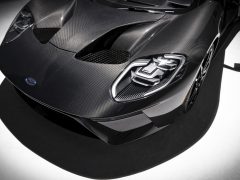 Close-up van een zwarte koolstofvezel Ford GT sportwagenkap en badge.