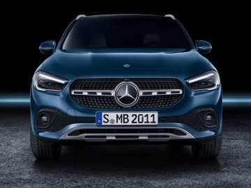 Vooraanzicht van een blauwe Mercedes-Benz GLA-auto tegen een donkere achtergrond.