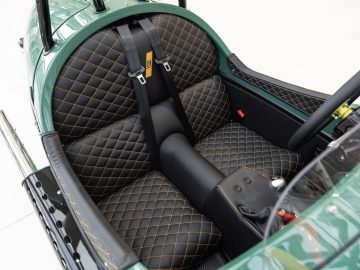 Binnenaanzicht van een vintage Morgan-auto met gewatteerde lederen stoelen met moderne veiligheidsgordels.