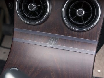 Dashboard met houten panelen in een luxe Morgan-auto met ronde ventilatieopeningen en een audiosysteemlogo met merklogo.