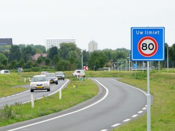 Een weg met een trajectcontrolesysteem dat een snelheidslimiet van 80 km/uur aangeeft.