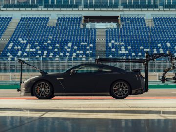 Sportwagen met open vleugeldeuren, geparkeerd in een pitlane op een racecircuit, die lijkt op een Nissan GT-R.