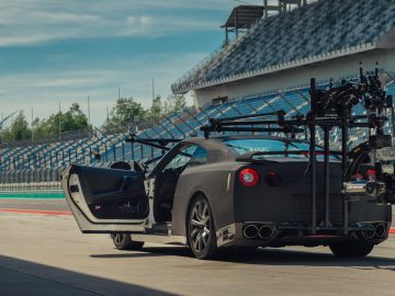 Een Nissan GT-R uitgerust met een professionele camera-installatie, geparkeerd in de pitlane van een racecircuit.