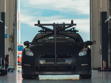 Zwarte Nissan GT-R sportwagen uitgerust met een bagagerek geparkeerd in een autowerkplaats.