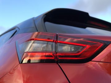 Close-up van het rode achterlichtontwerp van een Nissan Juke onder een blauwe lucht.