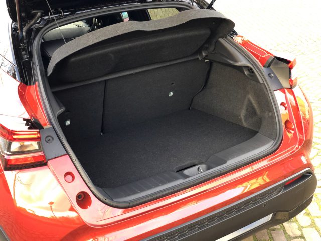 Lege kofferbak van een rode Nissan Juke met het luik open.