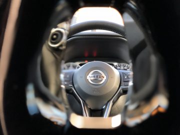 Stuur en dashboard van een Nissan Juke-voertuig gezien door een wazig helmvizier.