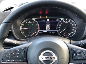 Bestuurdersaanzicht van het dashboard van een Nissan Juke-voertuig, met de bedieningselementen op het stuur en het instrumentenpaneel.