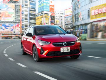 Rode Opel in beweging op een stadsstraat met een onscherpe achtergrond die de snelheid aangeeft.