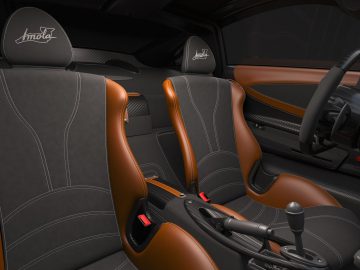 Binnenaanzicht van een Pagani Imola-sportwagen met zwart-oranje lederen stoelen, een handmatige versnellingspook en het logo geborduurd op de hoofdsteunen.