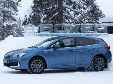 Blauwe Subaru Impreza e-Boxer-auto geparkeerd in de sneeuw voor een "boxer"-ijssculptuur.