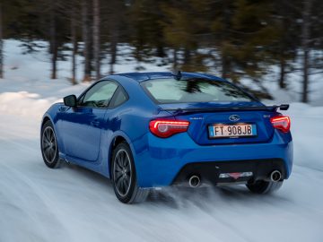 Subaru blauwe sportcoupé rijden op een besneeuwde weg.
