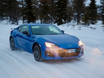 Blauwe Subaru sportwagen rijden op een besneeuwde weg met bewegingsonscherpte.