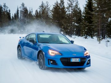 Blauwe Subaru-sportwagen die op een besneeuwde weg rijdt met bewegingsonscherpte die de snelheid aangeeft.
