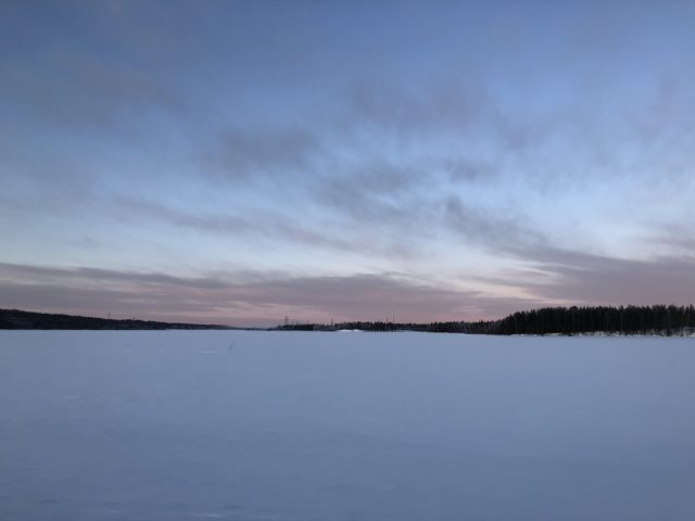Een rustige winteravond met een met sneeuw bedekt landschap, een pastelkleurige lucht in de schemering en een Subaru Forester die vlakbij geparkeerd staat, opgaand in het serene tafereel.