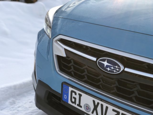 Blauwe Subaru XV e-Boxer met een Subaru-logo op de grille en een kentekenplaat in Europese Unie-stijl geparkeerd in de sneeuw.