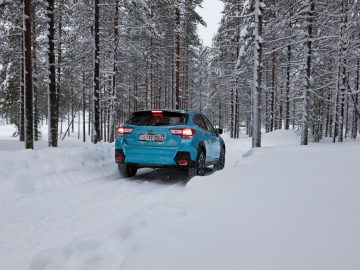 Een Subaru XV e-Boxer die door een besneeuwde bosweg rijdt.