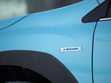 Close-up van het zijpaneel van een Subaru XV e-Boxer met "e-boxer"-badge en regendruppels.