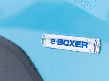 Blauw Subaru XV-autooppervlak met een nat "e-Boxer"-embleem en waterdruppels.