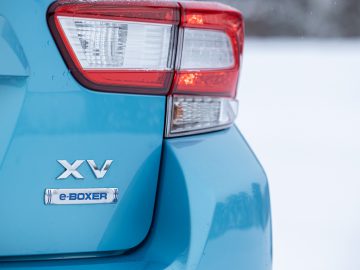 Close-up van een Subaru XV e-Boxer, gericht op achterlichtdetails tegen een besneeuwde achtergrond.