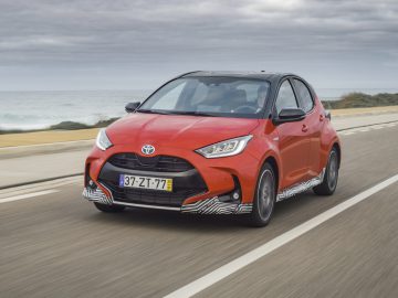 Een Toyota Yaris die over een kustweg rijdt.