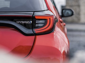 Close-up van het achterlicht en het kenteken van een rode Toyota Yaris hybride auto.