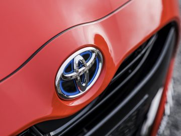 Close-up van de grille en het embleem van een rode Toyota Yaris.