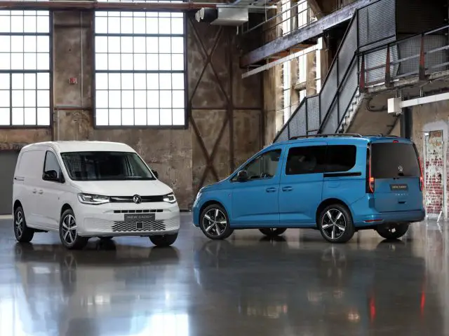 Twee Volkswagen Caddy-busjes geparkeerd in een gebouw in industriële stijl.