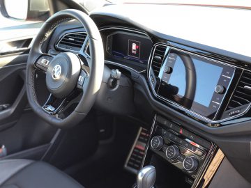 Binnenaanzicht van een moderne Volkswagen T-Roc R met een stuur met logo, een digitaal dashboard en een infotainmentsysteem met touchscreen.