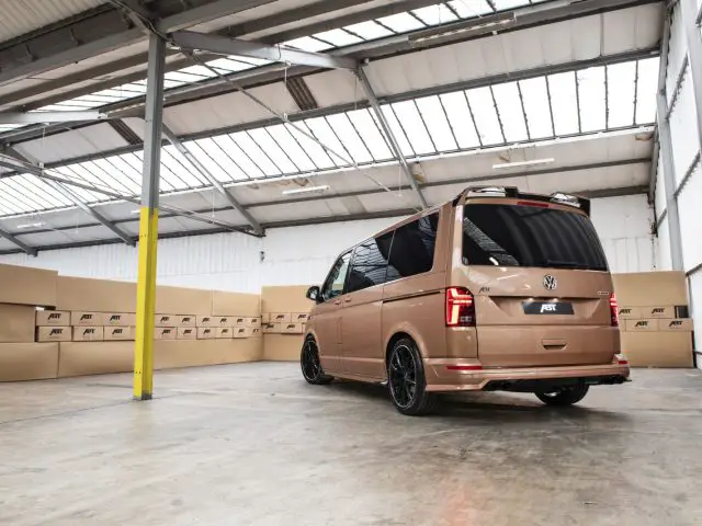 Een Volkswagen Transporter ABt-busje geparkeerd in een magazijn met kartonnen dozen tegen de muren gestapeld.