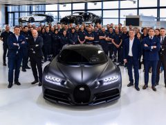 Team van ingenieurs en ontwerpers poseren met een Bugatti Chiron in een autowerkplaats.