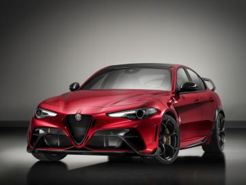Een rode Alfa Romeo Giulia GTA sportsedan tentoongesteld tegen een grijze achtergrond.