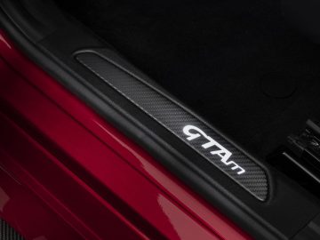 Close-up van de dorpel van een rode auto met een koolstofvezel 'Giulia GTA'-inscriptie.