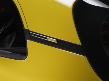 Close-up van de gele deur en luchtinlaat aan de zijkant van een Alpine A110.