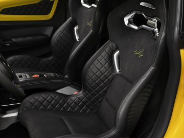 Luxe Alpine A110 auto-interieur met zwart lederen stoelen met gewatteerd ontwerp en gele stiksels.