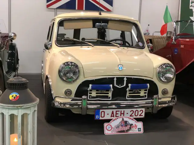 Vintage crèmekleurige mini-kuiper tentoongesteld op het Antwerp Classic Salon 2020 met een klassieke blauwe motorkapstreep en rallyverlichting.