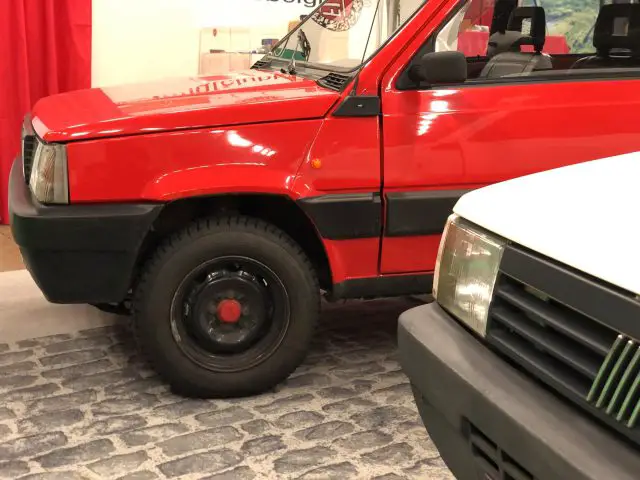 Rood-witte voertuigen te zien op het Antwerp Classic Salon 2020, met focus op het voorwiel en de bumper van de rode auto.