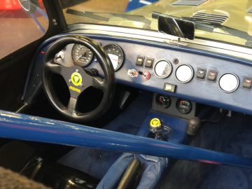 Binnenaanzicht van een vintage raceautocockpit van het Antwerp Classic Salon 2020 met een momo-stuur, een reeks tuimelschakelaars op het dashboard en een handmatige versnellingspook.