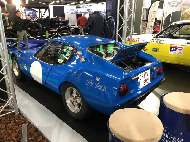 Blauwe vintage racewagen te zien op het Antwerp Classic Salon 2020 met andere voertuigen en tentoonstellingen op de achtergrond.