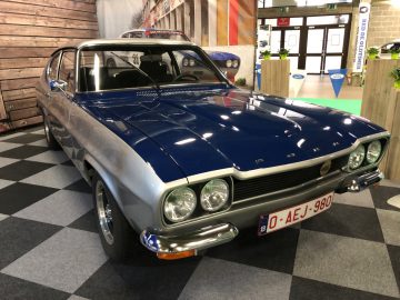 Een vintage blauwe en zilveren auto tentoongesteld op het Antwerp Classic Salon 2020 binnenshuis met een Belgisch kenteken.