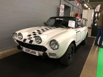 Witte vintage sportwagen met race-emblemen te zien op het Antwerp Classic Salon 2020.