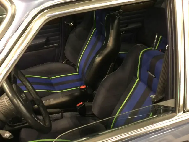 Binnenaanzicht van een auto op het Antwerp Classic Salon 2020 met sportstoelen met blauwe en groene strepen.