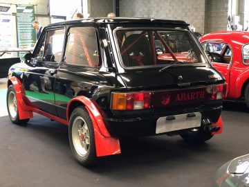 Een klassieke Abarth-sportwagen die binnen te zien is op het Antwerp Classic Salon 2020, met een zwart en rood kleurenschema.