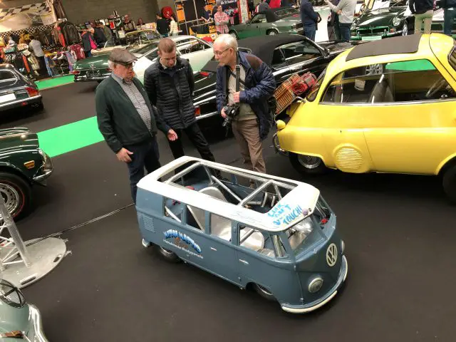 Drie mannen onderzoeken een miniatuur Volkswagenbus op de autoshow Antwerp Classic Salon 2020.