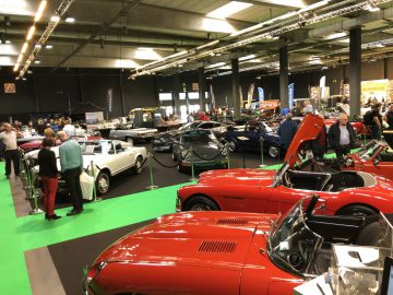 Een indoor klassieke autotentoonstelling waar verschillende oldtimers worden getoond aan een publiek op het Antwerp Classic Salon 2020.