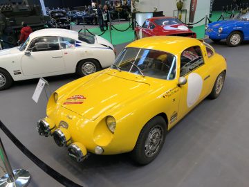 Vintage gele sportwagen met witte racerondels te zien op de autoshow Antwerp Classic Salon 2020.