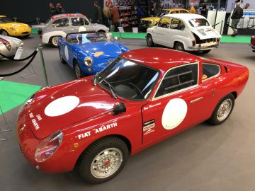 Rode Fiat Abarth-sportwagen tentoongesteld op het Antwerp Classic Salon 2020, versierd met race-emblemen.