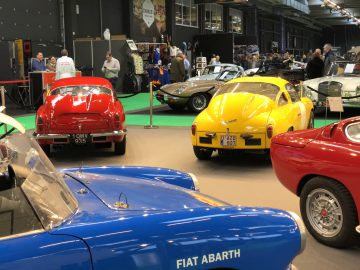 Oldtimertentoonstelling op Antwerp Classic Salon 2020 met een blauwe Fiat Abarth en andere klassieke auto's tentoongesteld met bezoekers op de achtergrond.