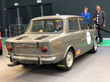 Een vintage Fiat Abarth tentoongesteld op het Antwerp Classic Salon 2020 met toeschouwers op de achtergrond.
